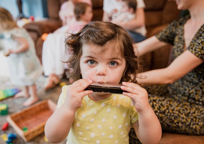 Jong meisje speelt mondharmonica