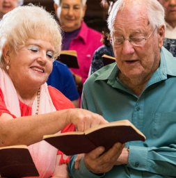 Twee oudere mensen in een koor die de songtekst aan het lezen zijn